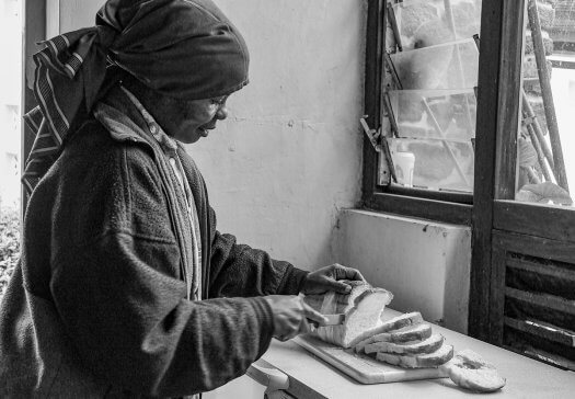 27 vrouw brood broodsnijden ontbijt tanzania zwart wit 5105 525x364